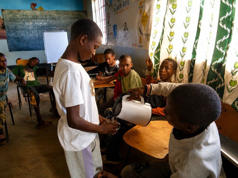 A teenager in a white T-shirt sharing refreshments with peers during a U-MATTER session